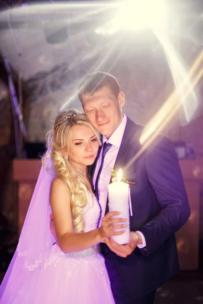 Portrait of the bride and groom at a banquet with a candle in hi