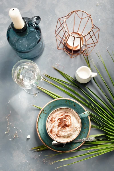 Cup of cappuccino set with modern accessories and palm leaf