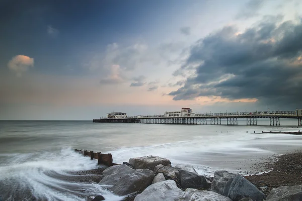Beautiful long exposure sunset landscape image of pier at sea in