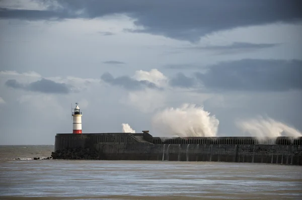 Large sea waves crashing over lighthouse during storm with beaut