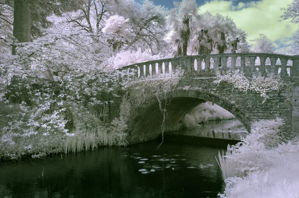 Stunning infrared landscape image of old bridge over river in co