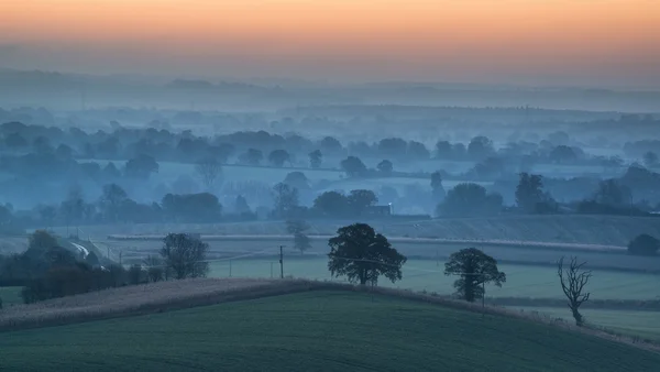 Stunning sunrise over fog layers in countryside landscape