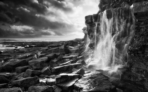 Beautiful landscape image waterfall flowing into rocks on beach