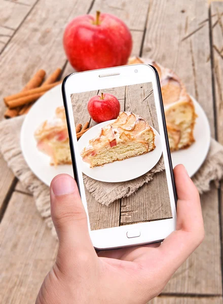 Hands taking photo apple cake with smartphone