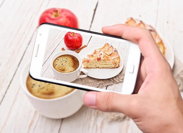 Hands taking photo apple cake with smartphone