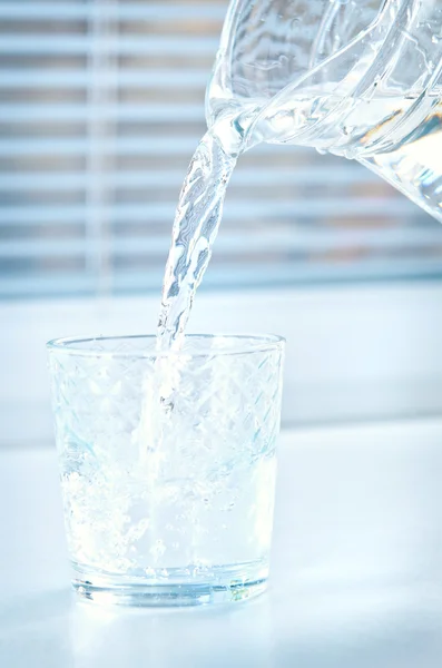 Pour water from a pitcher into a glass