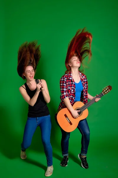 Two young women have fun, sing and play classical guitar