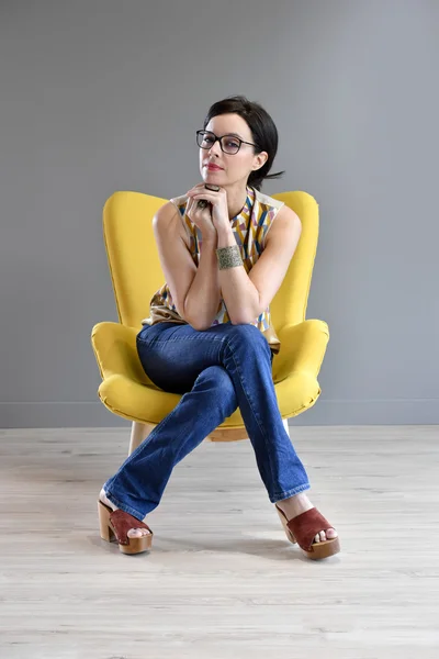 Woman relaxing in yellow armchair