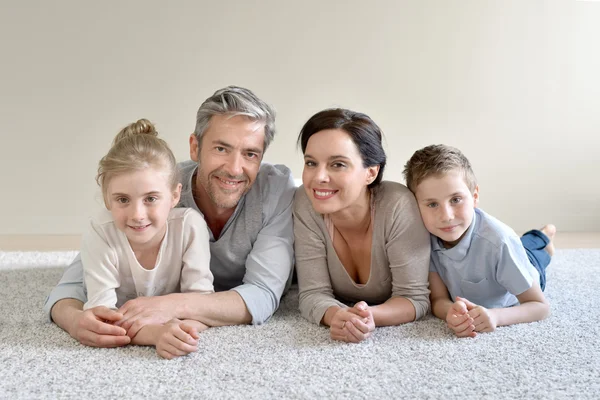 Cheerful family laying on carpet