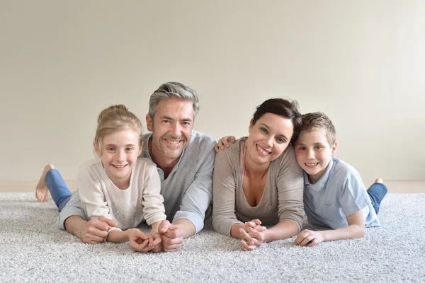 Cheerful family laying on carpet