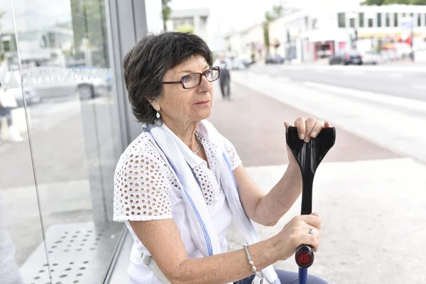 Woman with crutch waiting at bus stop