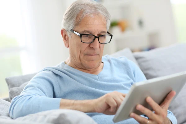 Senior man reading news on tablet