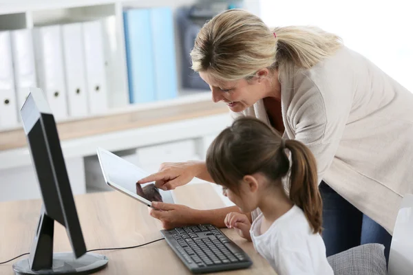 Teacher with girl using computer and tablet