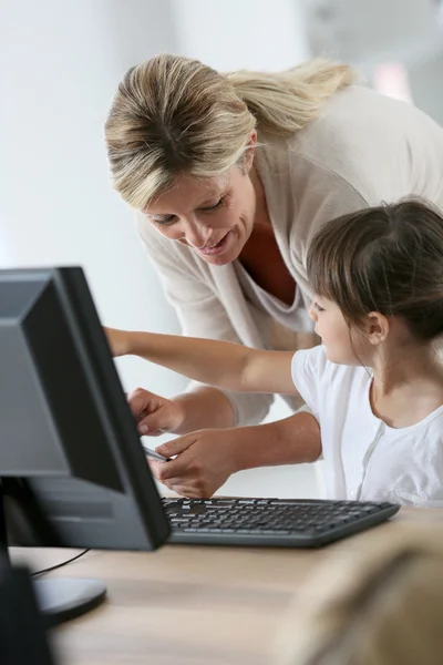 Teacher with girl using computer and tablet