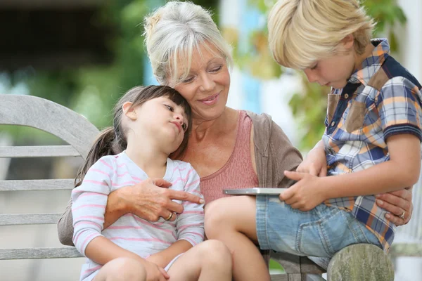 Grandmother with kids playing on tablet