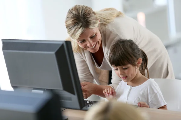 Teacher with girl using computer