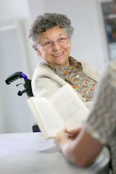 Home carer reading book to woman