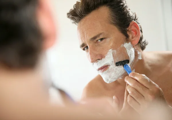 Man shaving in front of mirror