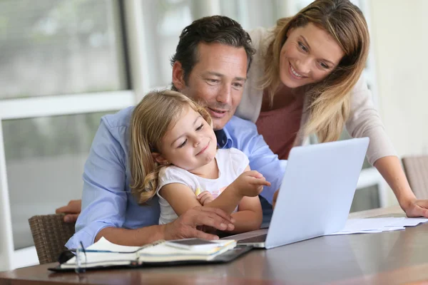 Parents with girl looking at pictures on computer