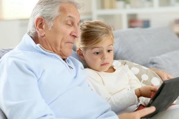 Girl with grandpa playing with digital tablet