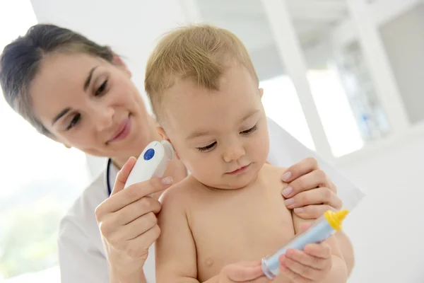 Pediatrician taking baby\'s temperature