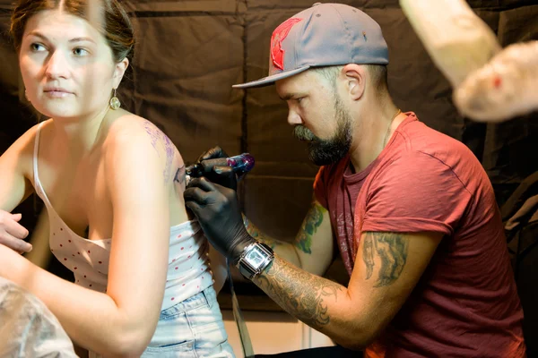 MINSK, BELARUS - SEPTEMBER 19, 2015: Professional tattoo artist doing tattoo on client.
