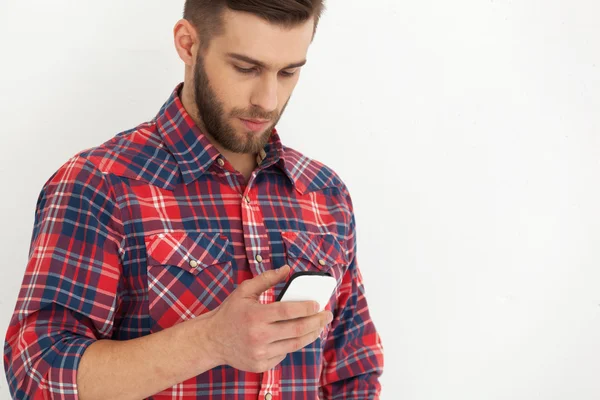 Handsome young man in casual wear typing text message.