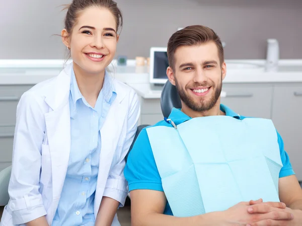 Portrait of a female dentist and young man in a dentist office.