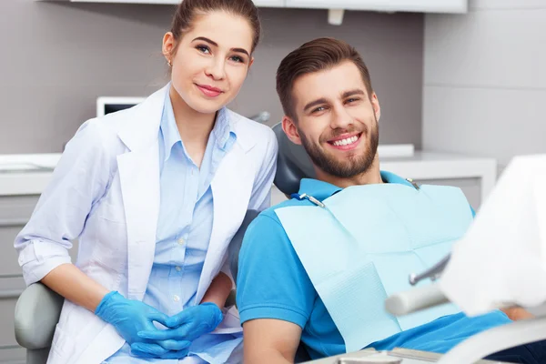 Portrait of a female dentist and young man in a dentist office.