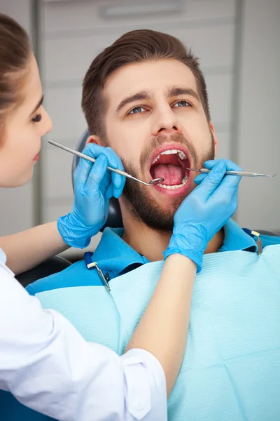 Young man getting his teeth checked by a dentist.