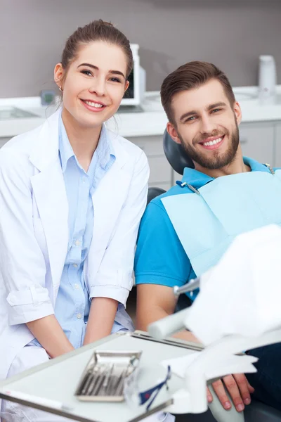 Portrait of a female dentist and young man in a dentist office.