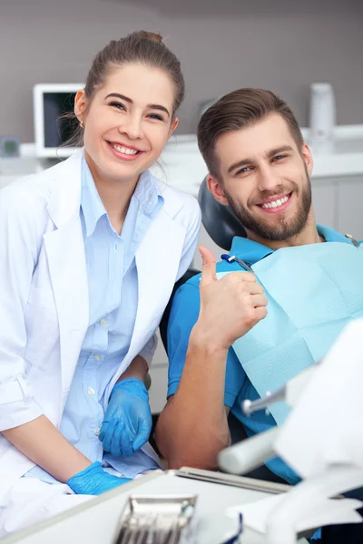 Happy young man in a dentist\'s chair giving a thumbs up.