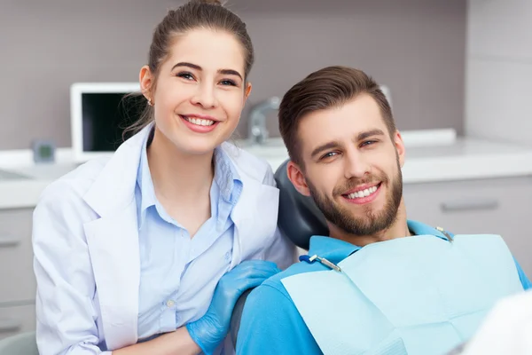 Portrait of a female dentist and young man in a dentist office.