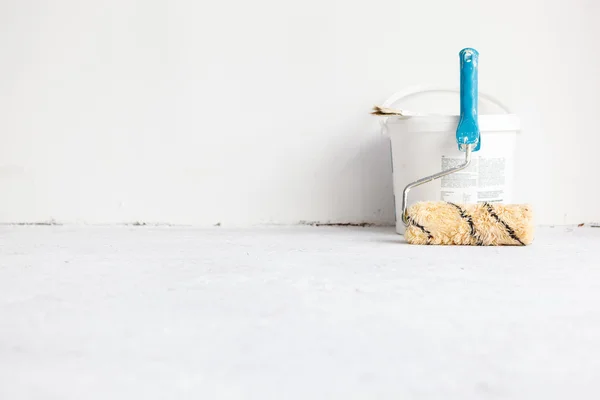 Paint bucket with roller brush on white.