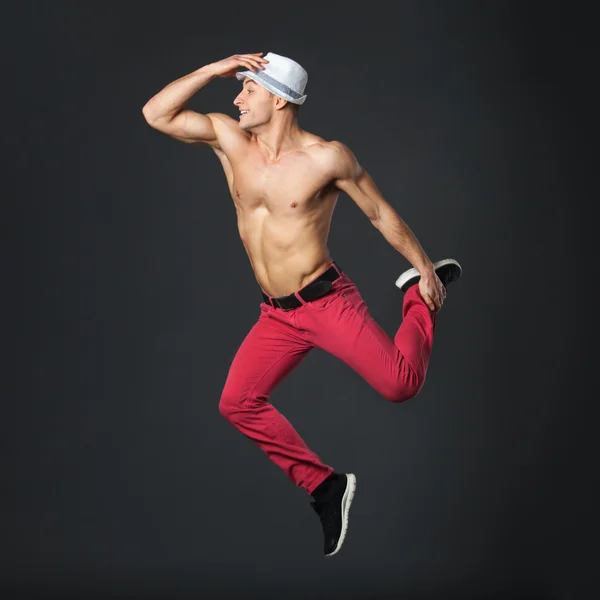 Young happy male dancer jumping in studio.