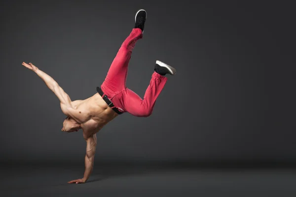 Young male professional dancer B-boying on gray background.