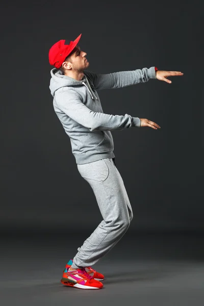 Fullbody portrait of young cool man dancing on dark background.