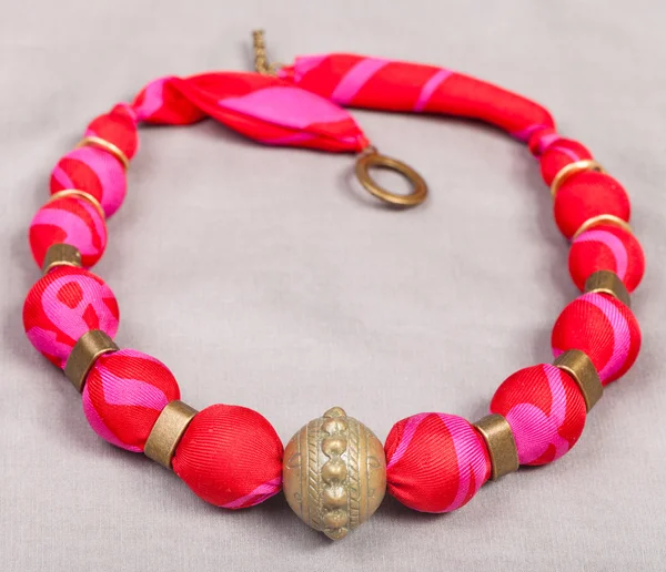 Necklace from red silk and bronze beads on gray