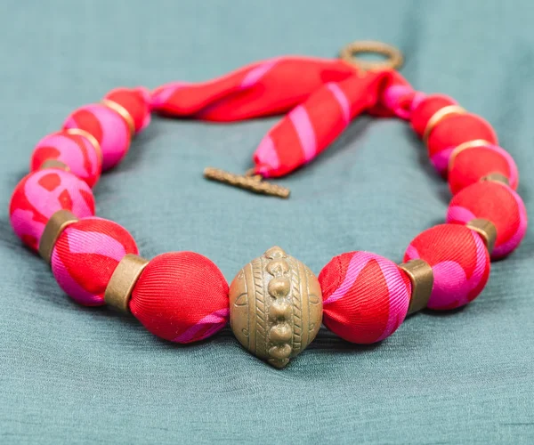Necklace from red silk and bronze beads on gree