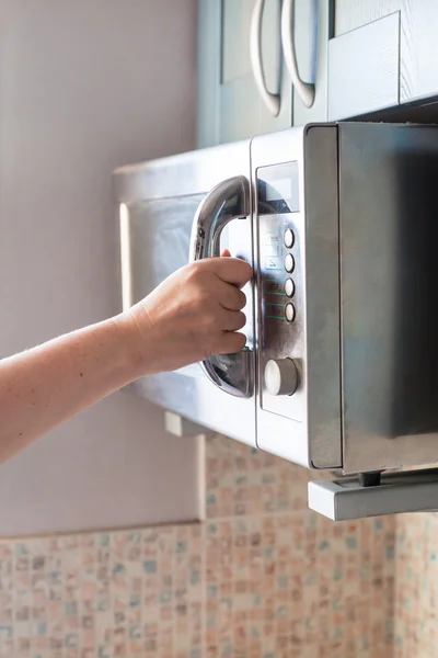 Hand closes microwave oven for heating food