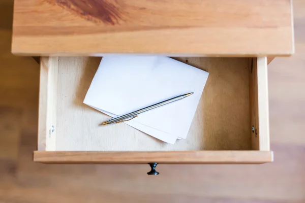 Folded sheet of paper and pen in open drawer
