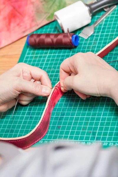 Craftsman sews belt for new leather bag