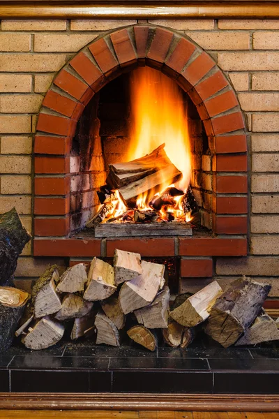Wood logs and fire in indoor brick fireplace