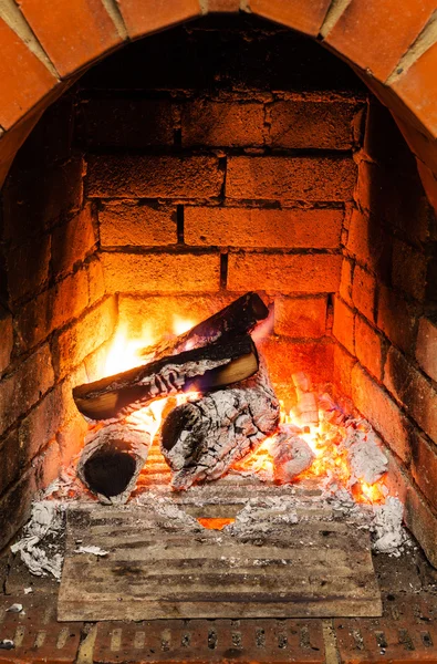 Ash, coal and burning wooden logs in fireplace