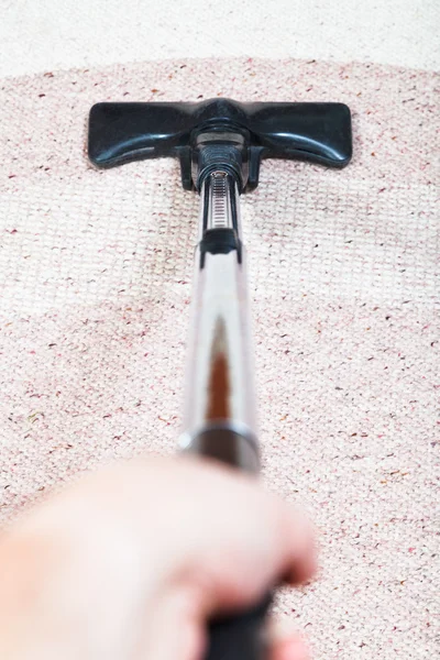 Man vacuuming the carpet by vacuum cleaner