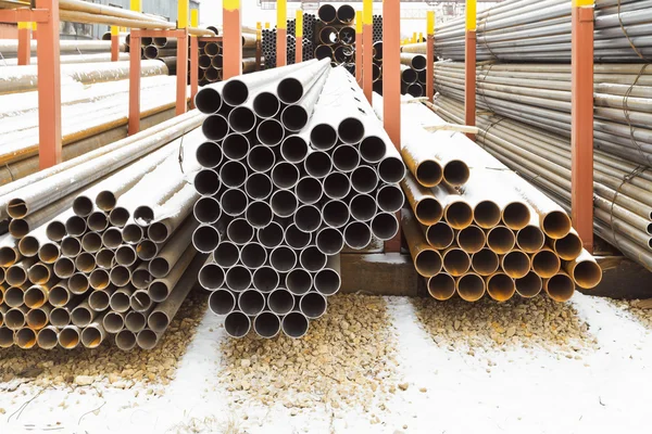 Piles of steel pipes in outdoor warehouse