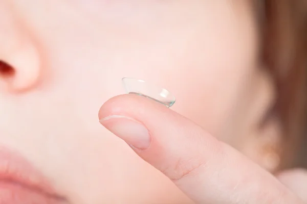 Contact lens on finger near female face