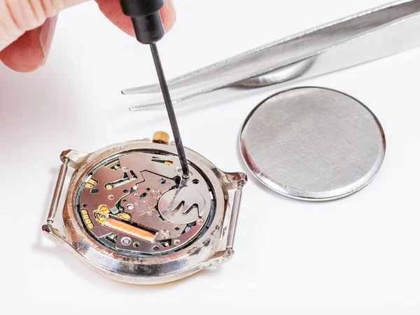 Repairer replaces battery in quartz watch close up