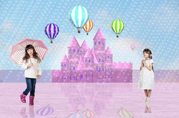 Two little girls in front of a pink fairy castle