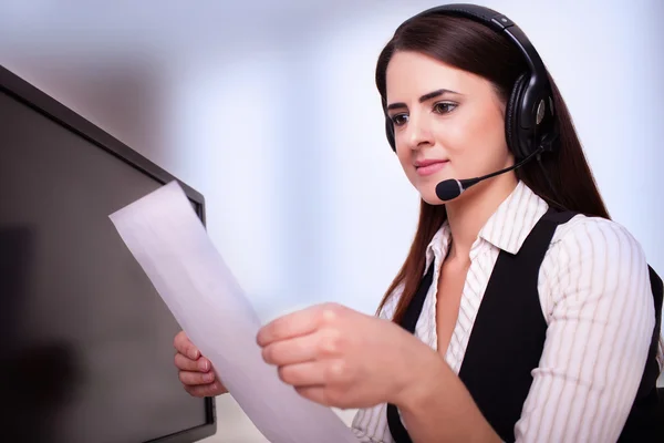 Mid adult businesswoman reading documents at office desk